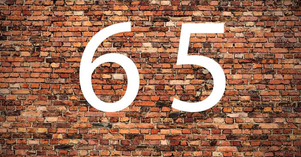 Die Zahl 65 in weiß vor einer Backsteinwand - Rohstoff Holz